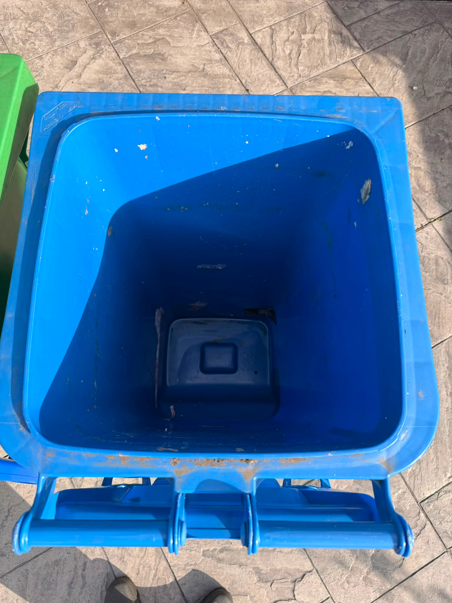 Inside of a blue wheelie bin with debris before cleaning