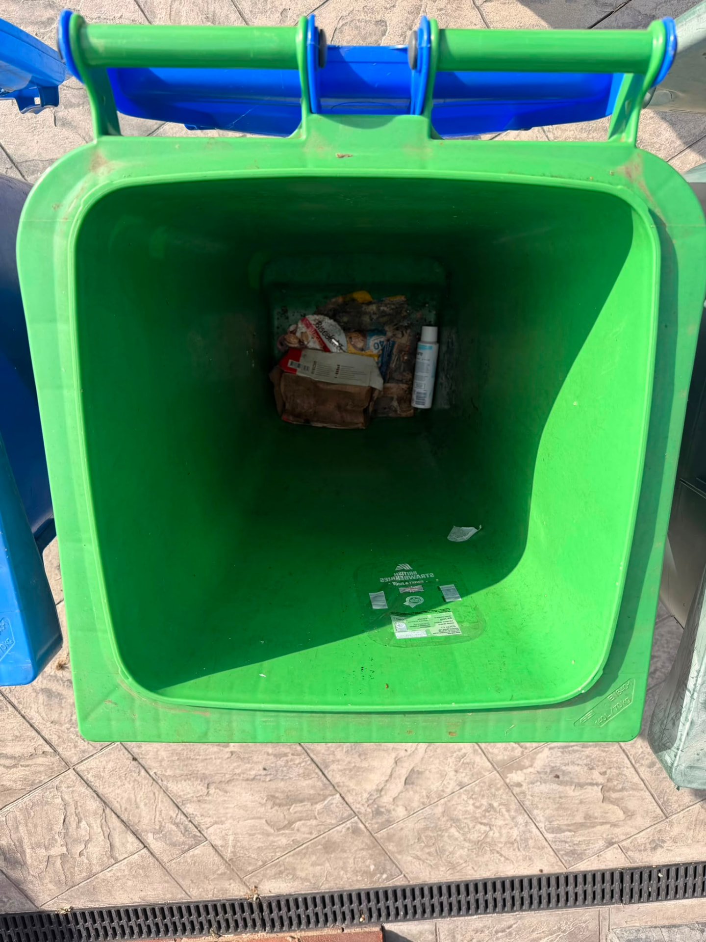 Inside of a green wheelie bin with leftover rubbish and residue before a professional bin clean